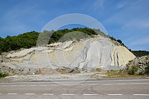 slope of the mountain with layers of sedimentary rocks. Vertically located sedimentary rocks on collapsing hillside