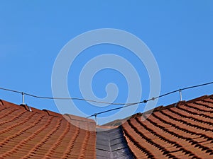 sloped clay tile roof valley with zink valley flashing. ridge tiles and metal rod lightning protection rod