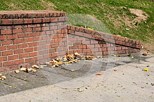 Sloped end piece of old brick retaining wall, concrete with magnolia leaves