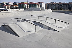 Sloped metal rails for grind tricks in an empty concrete skatepark