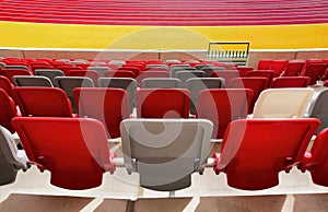 seating area detail of sport Stadium. curving rows of colorful plastic seats on steel frame.