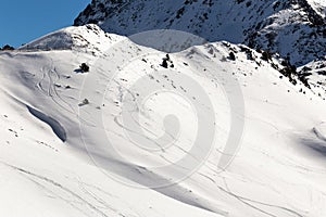 The slopes of the mountains in the snow with traces of skis.