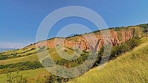 Slopes of Rapa Rosie, the grand canyon of Romania, with orange rocks and green meadows