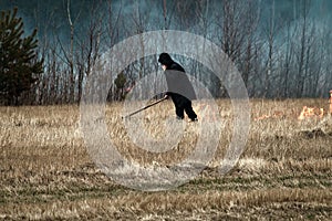 sloping field and a man sets fire to dry grass