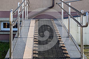 Sloping walkway surrounded by shiny handrails with antislip coating designed for wheelchair lift facility or infants in pram photo