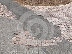 Sloppy brick sidewalk repair. Brick walkway patched with asphalt after construction project