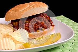 Sloppy Joe sandwich with chips and pickle photo