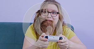 Sloppy nervous woman bites hair playing video game console