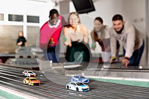 Slot car racing track. Emotional players drive toy cars