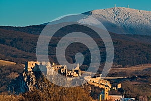 Slovak ancient castle Beckov with snowy top of Povazsky Inovec mountain during sunset in winter months