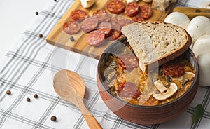 Slovak Christmas national cabbage soup in ceramic bowl with sausage on the tablecloth background