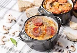 Slovak Christmas national cabbage soup in small black pot with sausage on the tablecloth background