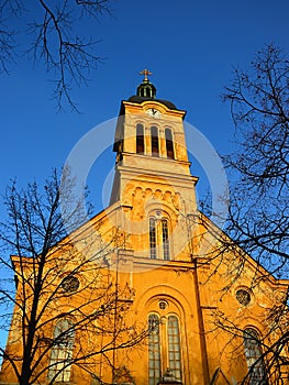Slovenský evangelický augsburský kostel v Modre ve večerním jarním slunci, jasná modrá obloha, viditelné průčelí s věžními hodinami.