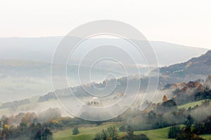 Slovak rural mountain landscape, valley with forest and small houses. Late autumn. Foggy early morning