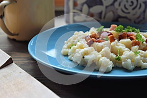 Slovak traditional potato gnocchi with sheep cheese and bacon,wooden table