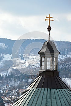 Slovak twin cross placed on baroque building of central church of calvary in Banska Stiavnica, Slovakia, snow covered hills i