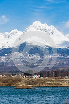 Slovakia: Big Tatras Vysoke Tatry on the spring. Big mountains with the snow and clouds. The lake in foreground. Small village n