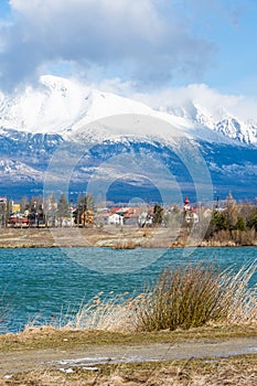 Slovakia: Big Tatras Vysoke Tatry on the spring. Big mountains with the snow and clouds. The lake in foreground. Small village n