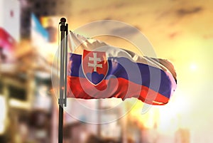 Slovensko vlajka proti město rozmazané pozadí při východu slunce podsvícení