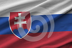 Slovenská vlajka s velkými záhyby vlající zblízka pod studiovým světlem v interiéru. Oficiální symboly a barvy v banneru