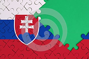 Slovakia flag is depicted on a completed jigsaw puzzle with free green copy space on the right side