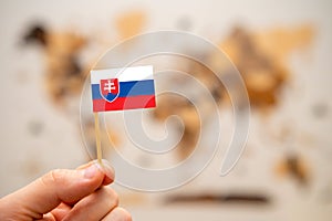 Slovakia flag in mans hand on the world map background.