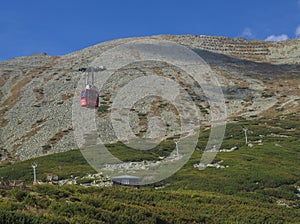 Slovakia, High Tatra mountain, September 13, 2018: Red cable car cabine going on mountain Peak Lomnicky stit 2 634 m, scrub pines