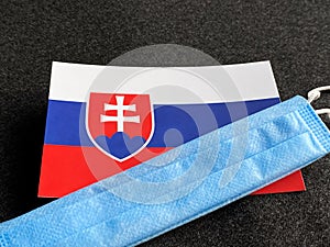 Slovensko, slovenská vlajka je blízko modrej masky na tmavosivom pozadí. Turistický výlet. Majstrovstvá Európy vo futbale