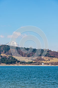 Slovensko: Malá vesnice poblíž Tater. Jezero Liptovská Mara v popředí. Zima a sněhová hora.