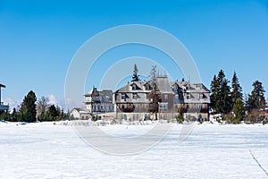 Slovakia: Strbske pleso resort, view of frozen lake in winter and hotel resort above. Blue sky.