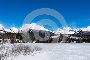 Slovakia, Strbske Pleso: View of frozen lake in Big Tatra, Slovakia. Mountains in background, the trees and lake in foreground. Wi