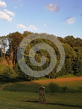 Slovenia, rural evening landscape with meadow, field and forest, hunter watch tower