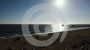 Slow Aerial Dolly shot of the Huntington Beach Pier and Beach shot into the setting sun.