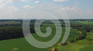 Slow aerial fly over of green crop fields with a blue sky