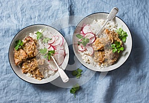 Slow cooker pork tenderloin with rice pilaf and radish salad on a blue background, top view.