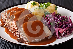 Slow Cooker Pot Roast Sauerbraten with spicy sauce, potato dumplings and red cabbage close-up. horizontal photo