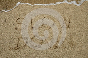 Slow down, mindfulness concept written on sand