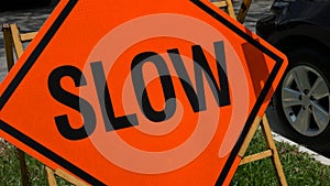 Slow down red banner traffic sign on the road with car in background.