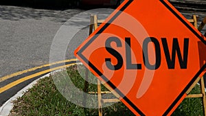 Slow down red banner traffic sign on the road with car in background.