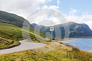 Slow-driving car on single wavy, serpentine road in North Coast 500, Scotland