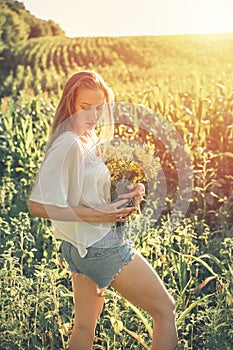 Slow Living concept New Lifestyle Trend. Relaxing young woman with lowers in nature, in corn, sunflower field