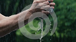 Slow motion 180fps: Man squeezes soaking wet shirt in rainstorm