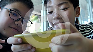 Slow motion 4K Happy asian boy playing mobile game online on smart phone together . Boy and friend confer with strategy having fu