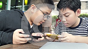 Slow motion 4K Happy asian boy playing mobile game online on smart phone together . Boy and friend confer with strategy having fu