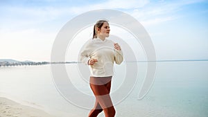 Slow motion of active and fit young woman running on the beautiful sandy beach, embodying the importance of physical activity and