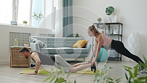 Slow motion of active young people couple doing sports at home together training indoors