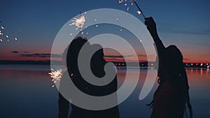 Slow motion of adventurous young people having fun dancing with sparklers at night