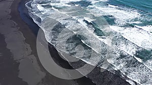 Slow motion aerial above view of Atlantic ocean waves washing volcanic black sandy beach, Iceland