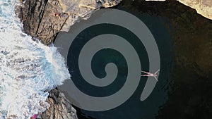 Slow motion aerial view of girl floating in Giola natural sea pool Thassos island, Greece