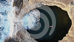 Slow motion aerial view of girl floating in Giola natural sea pool Thassos island, Greece